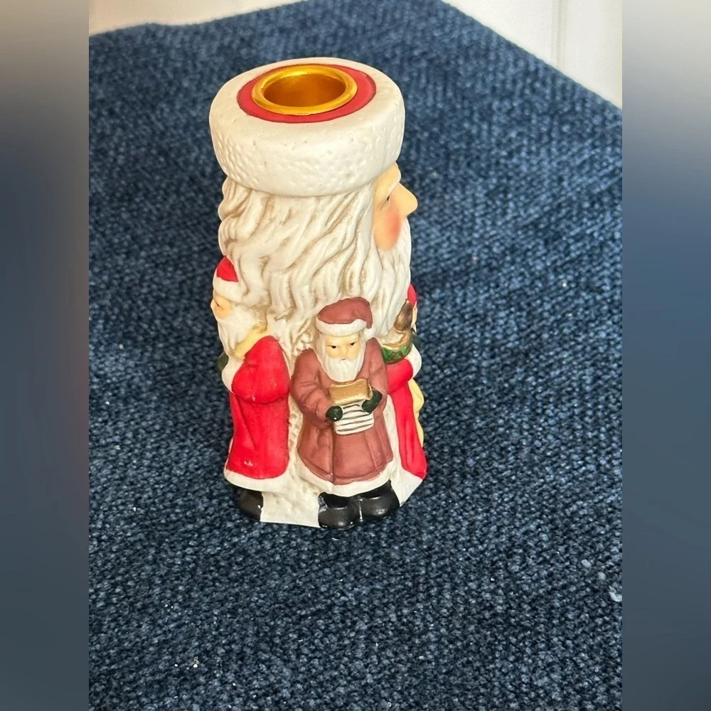 Cute Santa ceramic candleholder. Multiple smaller Santas surrounding the holder.